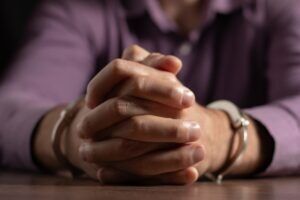 A close-up of a man’s hand who is in custody for murder in Arizona. How does Arizona classify first-degree vs. second-degree murder?