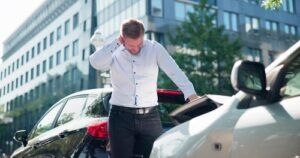 Distressed man standing between two cars after a crash