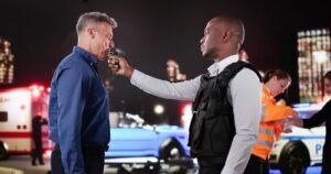 Police officer giving a breathalyzer test at an accident scene