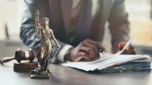 Attorney reviewing case files beside a Lady Justice statue