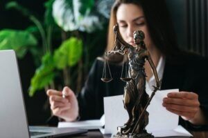 Attorney reviewing documents beside a Lady Justice statue