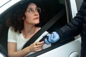 woman in car receiving breathalyzer device from gloved officer during traffic stop